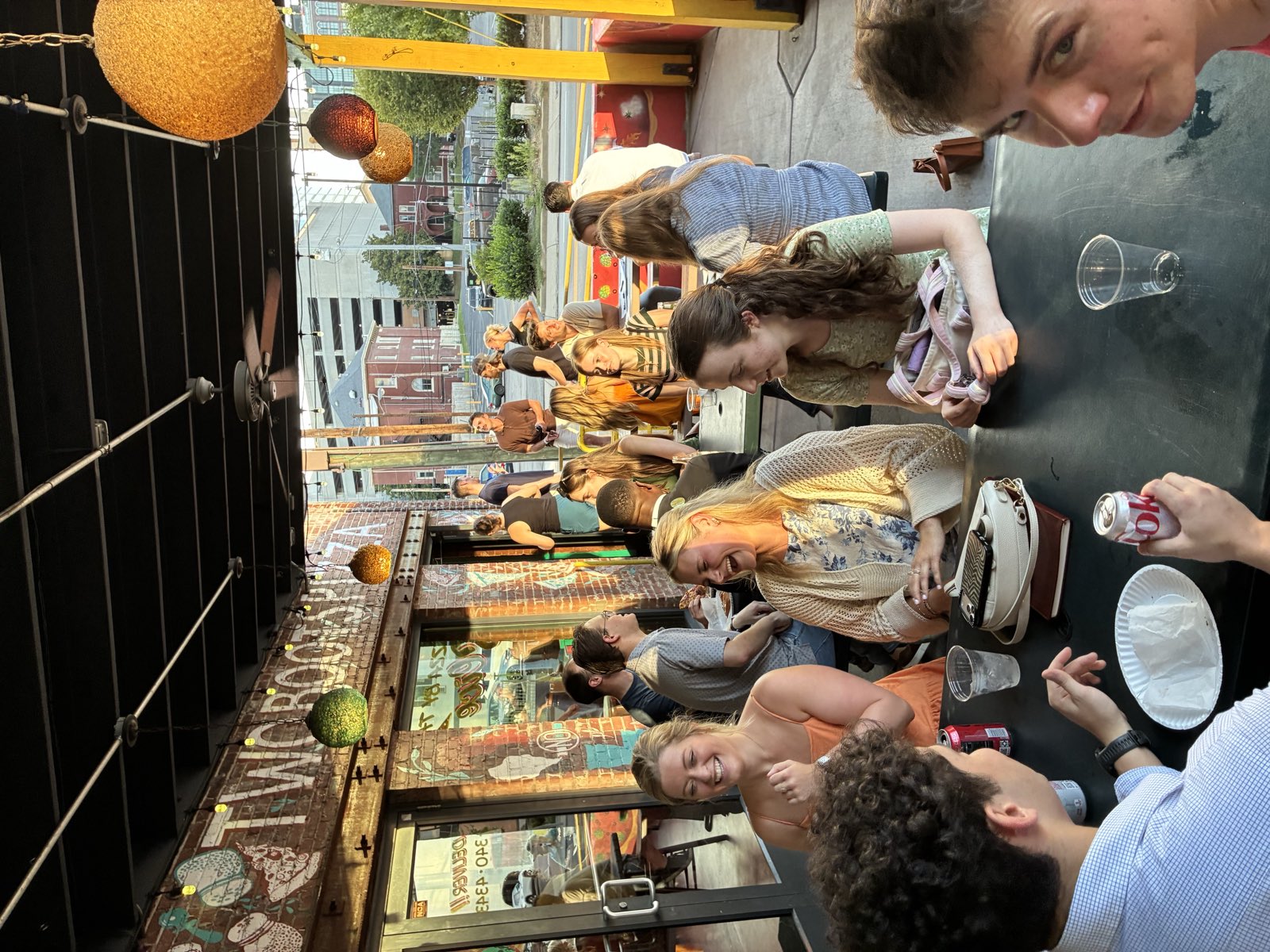 Post Mass crowd on the Two Boots Pizza patio at golden hour