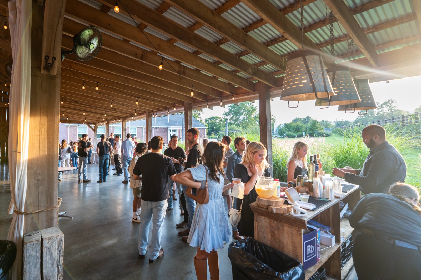 Golden-hour crowd mingling at the bar under the pavilion
